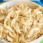 Shredded cooked chicken served in a large white bowl with a text overlay on the photo