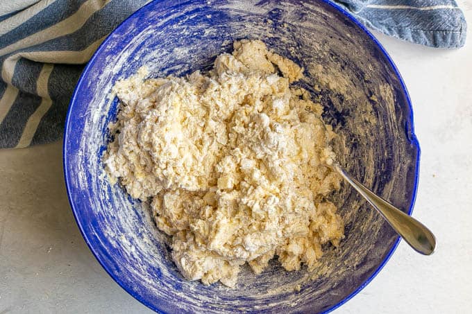 Biscuit dough being mixed in a large blue bowl