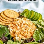 A mound of buffalo chicken salad atop mixed greens in a salad bowl with cucumber slices and whole grain crackers and a text overlay on the photo