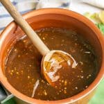 A small sauce pan with a wooden spoon resting in some homemade teriyaki sauce and a text overlay on the photo