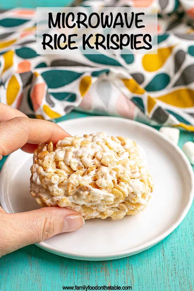 A hand picking up a Rice Krispie treat from a small white plate with a text overlay on the photo