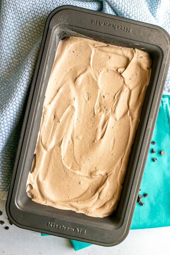 Creamy, smooth chocolate ice cream in a small pan after being frozen with mini chocolate chips scattered nearby