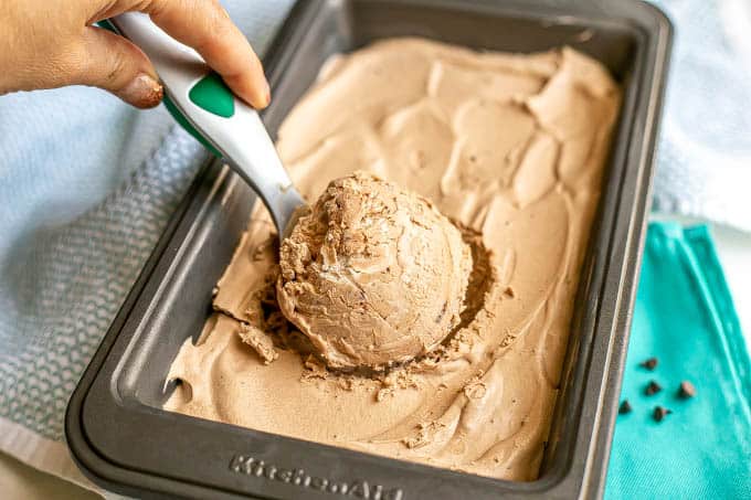 A scoop of homemade chocolate ice cream being taken from a small pan