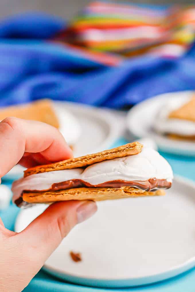 Close up of a hand holding a baked s'mores sandwich