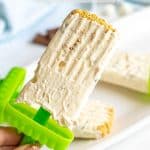 A hand holding a homemade s'mores popsicle with graham cracker crumbs on the top and a text overlay on the photo