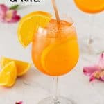 A wine glass with an Aperol Spritz cocktail and orange slices with a text overlay on the photo