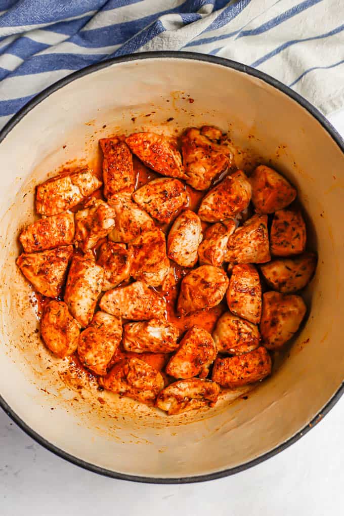 Seared cubed chicken breast pieces in a large purple pot