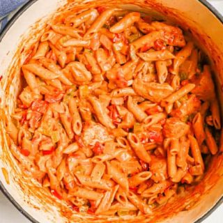 A creamy pasta with chicken, tomatoes and veggies in a large purple pot