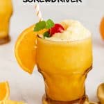 An amber glass with a slushy frozen screwdriver garnished with orange slice, cherry and a sprig of mint and a text overlay on the photo
