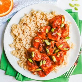 Orange chicken served over steamed brown rice with green onions sprinkled on top