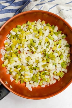 Sauteed onion and peppers in a large copper skillet