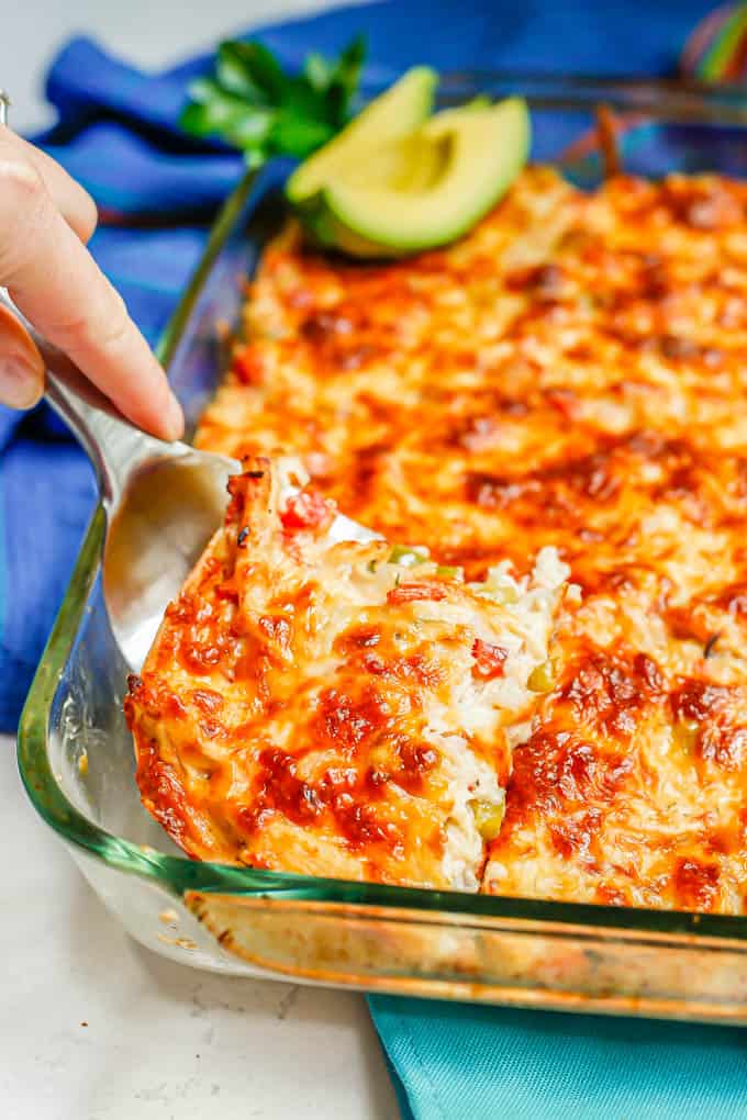 A spatula lifting out a slice of King Ranch chicken from a casserole baking dish