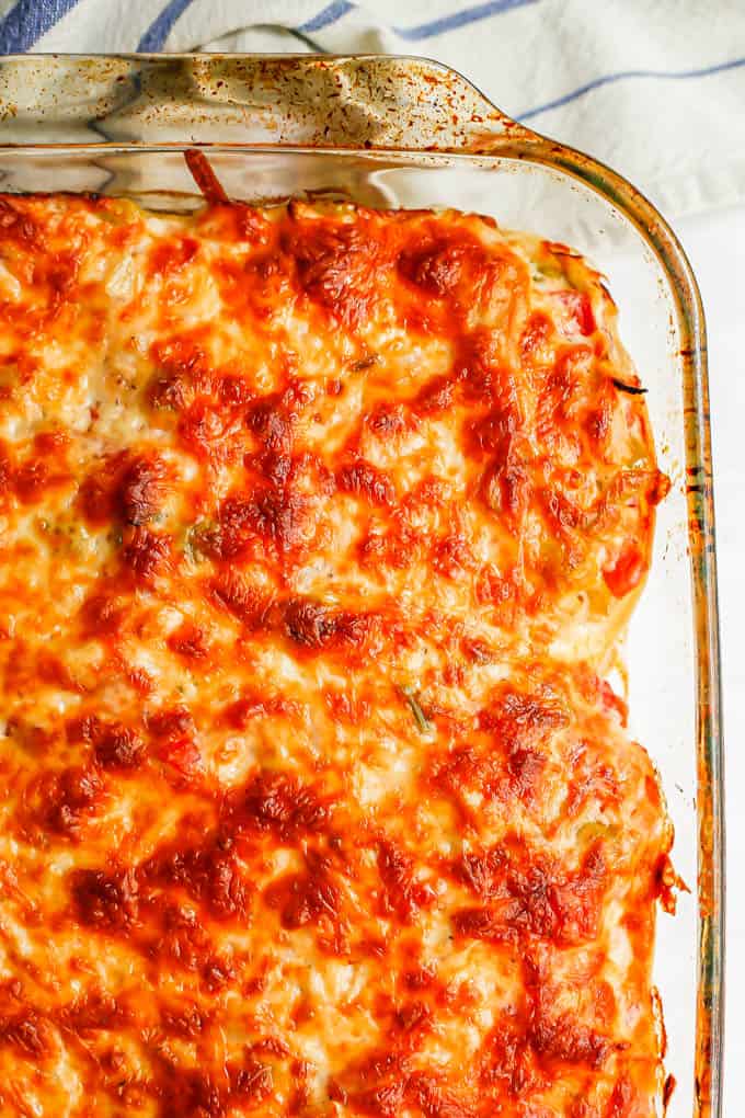 Close up of a browned baked cheesy chicken casserole in a glass casserole dish