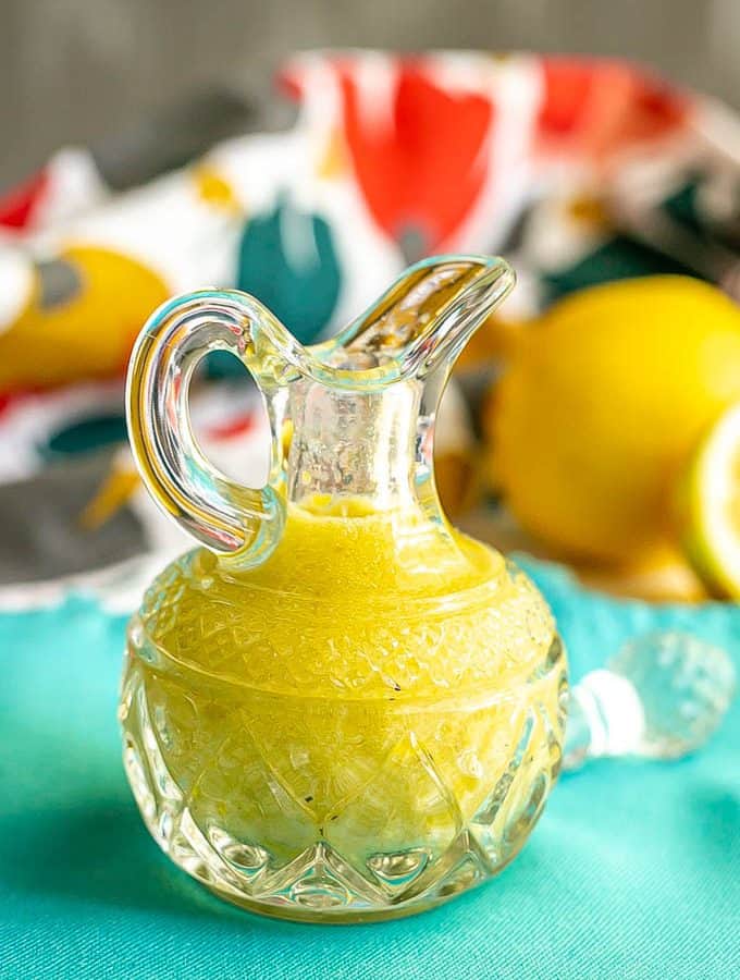A yellow lemon vinaigrette in a small glass crystal jar