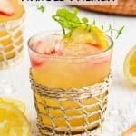 A short clear glass with a lemonade tea and bourbon drink plus lemon and strawberry garnishes and a text overlay on the photo