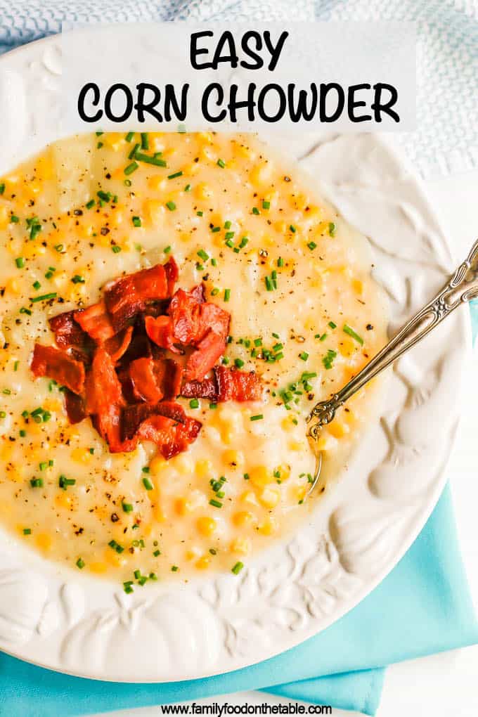 Corn chowder with bacon and chives served in an white bowl with a spoon resting in it and a text overlay on the photo