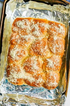 Pizza sliders brushed with butter and sprinkled with Parmesan cheese before being baked