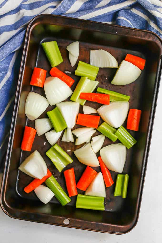 A mix of raw carrots, celery and onion in a roasting pan before being cooked