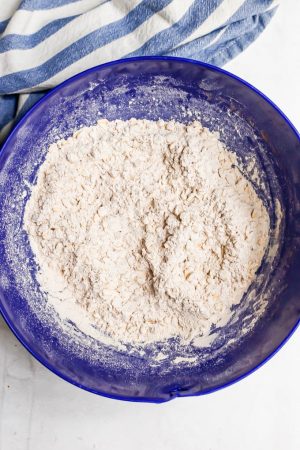 A blue mixing bowl with a flour and oat dry mixture
