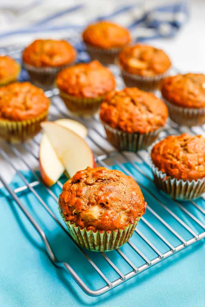 A cooling rack with apple cider muffins and a couple of apple slices