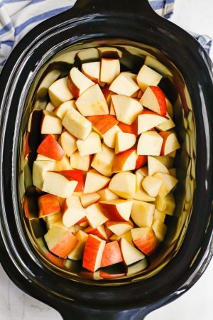 Chopped apples in the insert of a slow cooker before being cooked