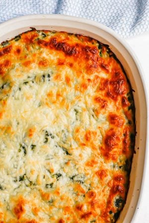 Close up of a baked casserole dish with a cheesy spinach dip