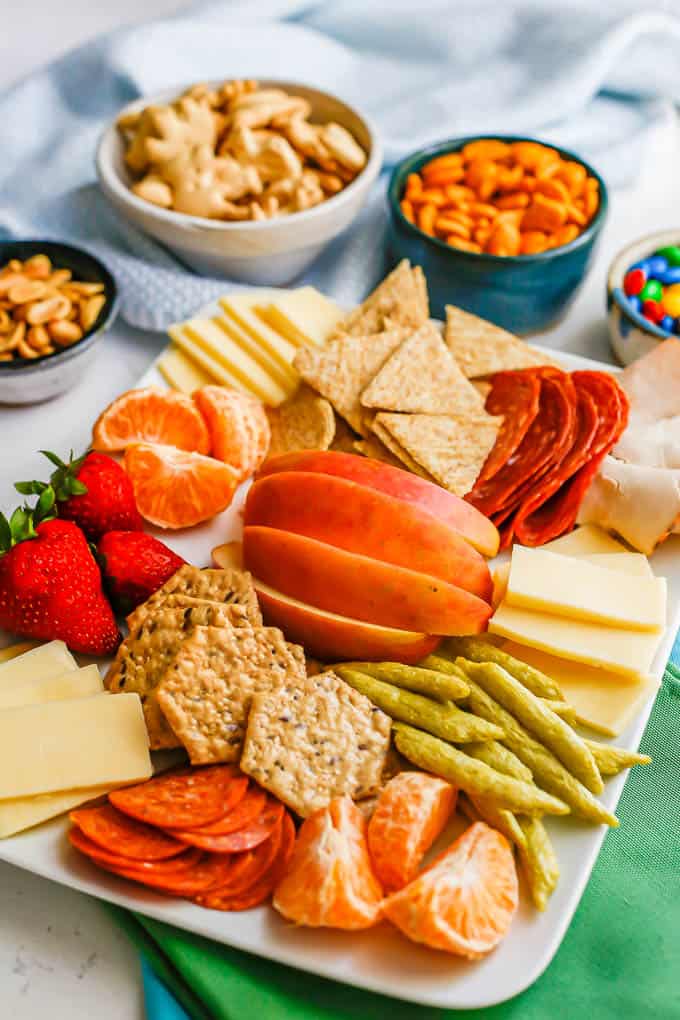 Side angle view of a big snack board with extra bowls in the back for more snacks