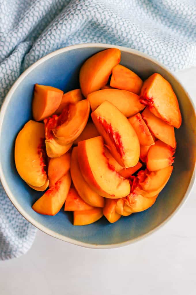 A blue bowl with fresh sliced peaches