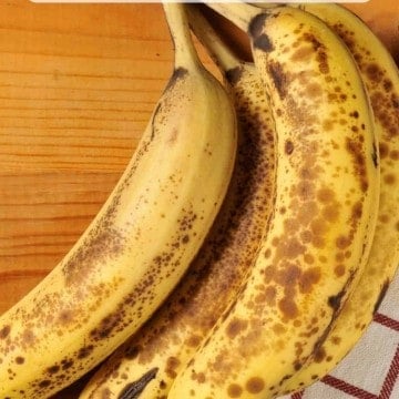 A bunch of ripe bananas on a wooden counter with a text overlay on the photo