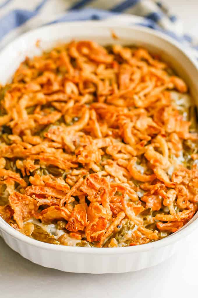 A white oval baking dish with green bean casserole topped with crunchy French fried onions