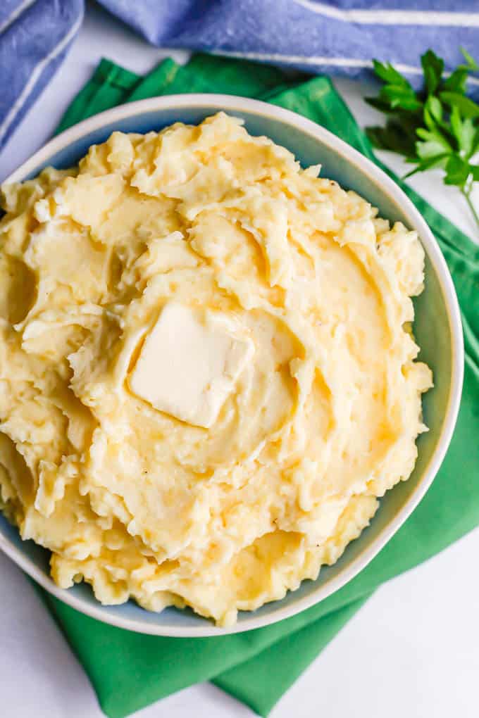 Homemade Yukon mashed potatoes served in a blue and white bowl with a pat of butter on top