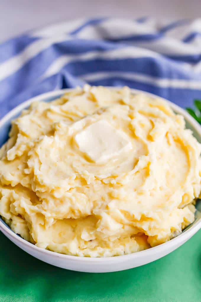 Close up of homemade mashed potatoes in a serving bowl with a pat of butter on top