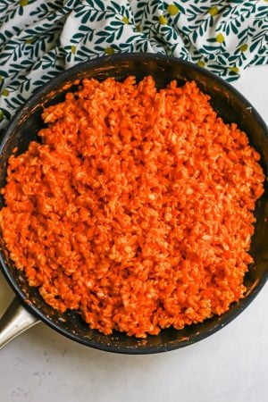 Orange Rice Krispies being made in a large skillet