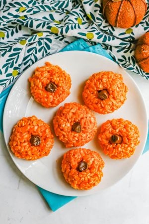 Overhead shot of a white plate of orange pumpkin Rice Krispies with tootsie roll stems