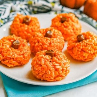 A plate full of rice Krispie treats in the shape of pumpkins with a tootsie roll for a stem