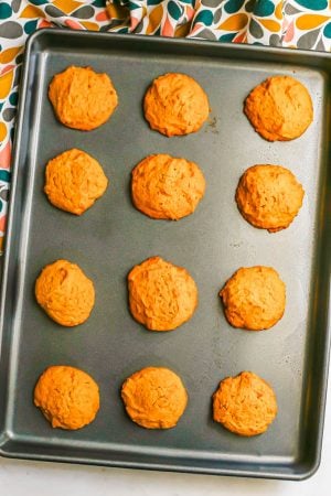 A baking sheet with a dozen pumpkin cookies after being baked in the oven