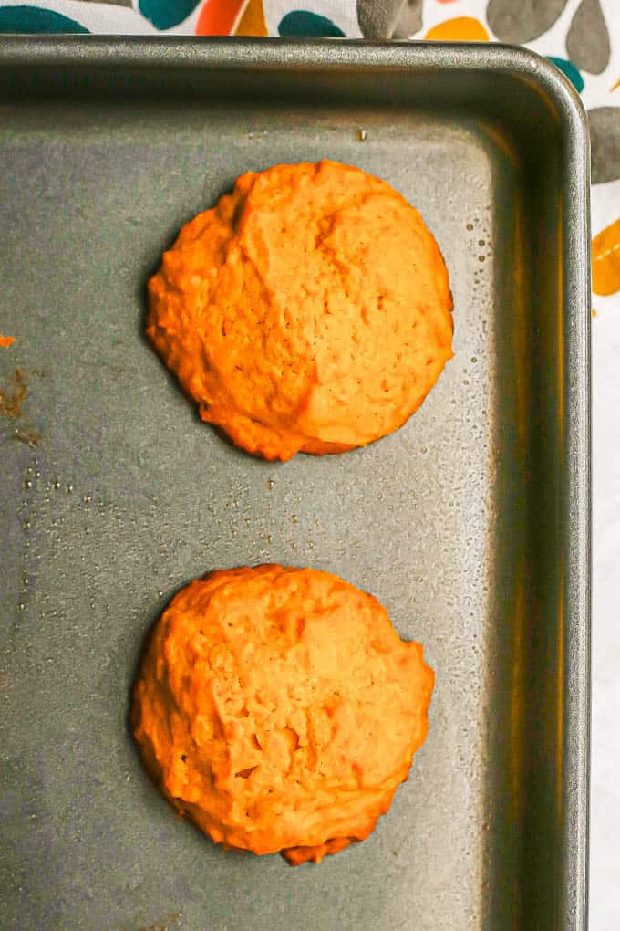 Close up of two baked soft pumpkin cookies on a baking tray