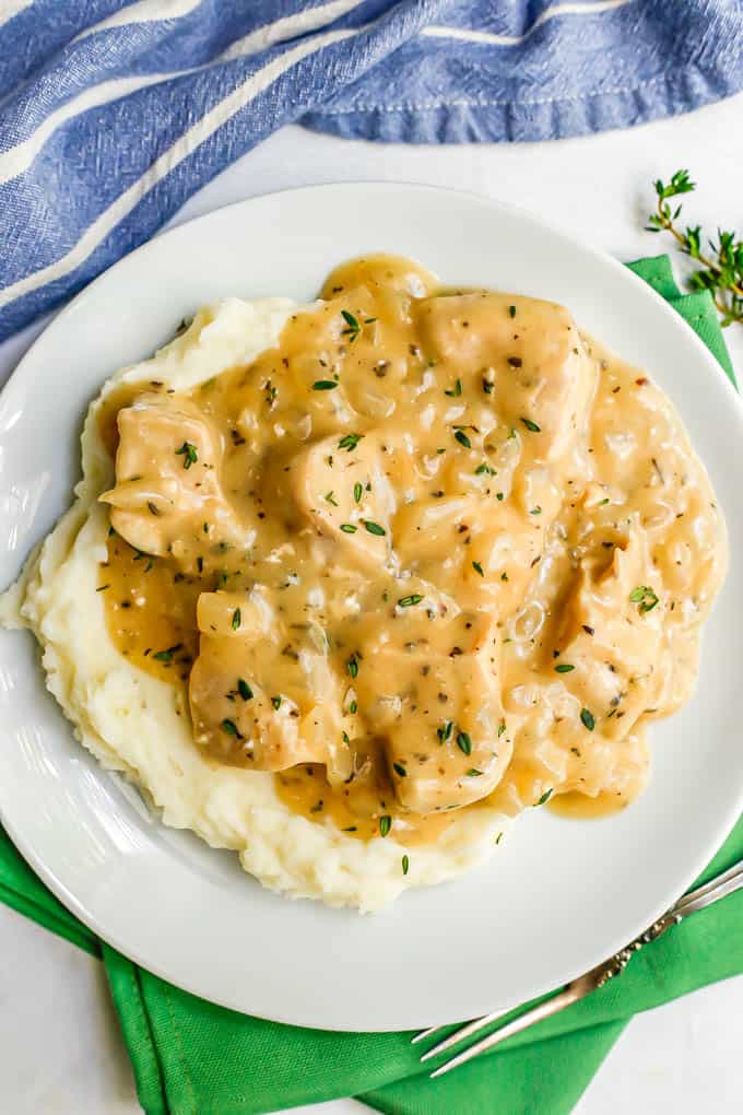 Overhead of chicken and gravy over mashed potatoes on a white plate set on green napkins