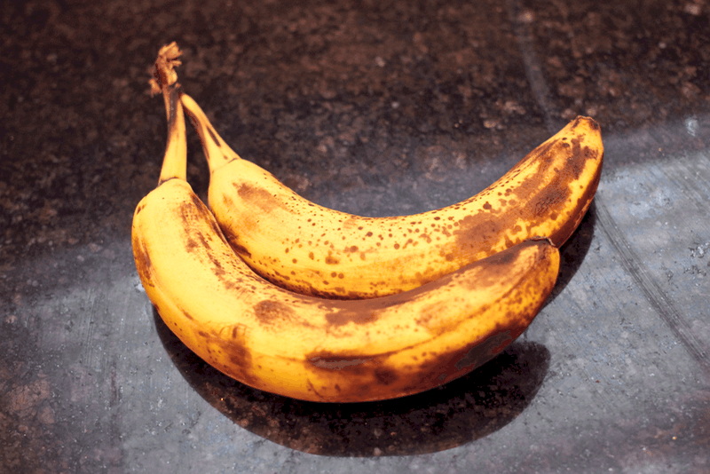 Two ripe bananas on a dark marble counter