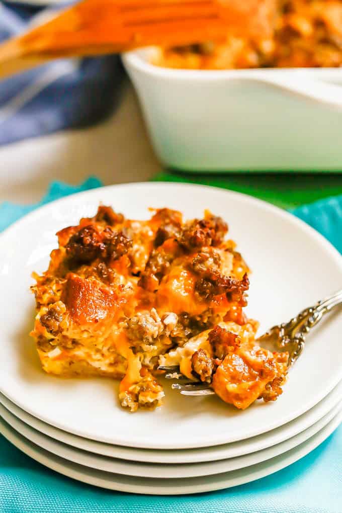 A square piece of a breakfast casserole plated on a small white plate with a fork resting to the side with a bite of food