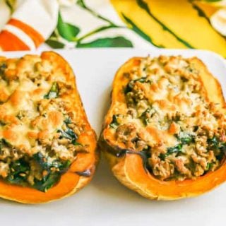 Two halves of a butternut squash stuffed with sausage and spinach and topped with Parm cheese