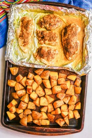 Roast chicken on a foil lined tray on a sheet pan with roasted potatoes on the other side