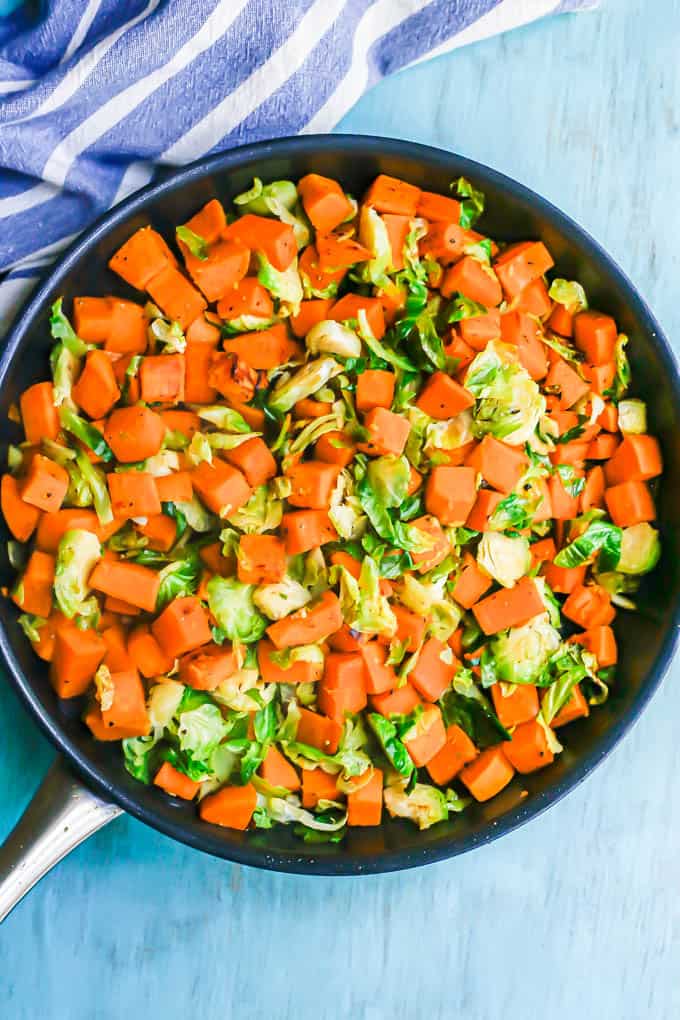 A skillet with cooked, tender diced sweet potatoes and shredded Brussels sprouts