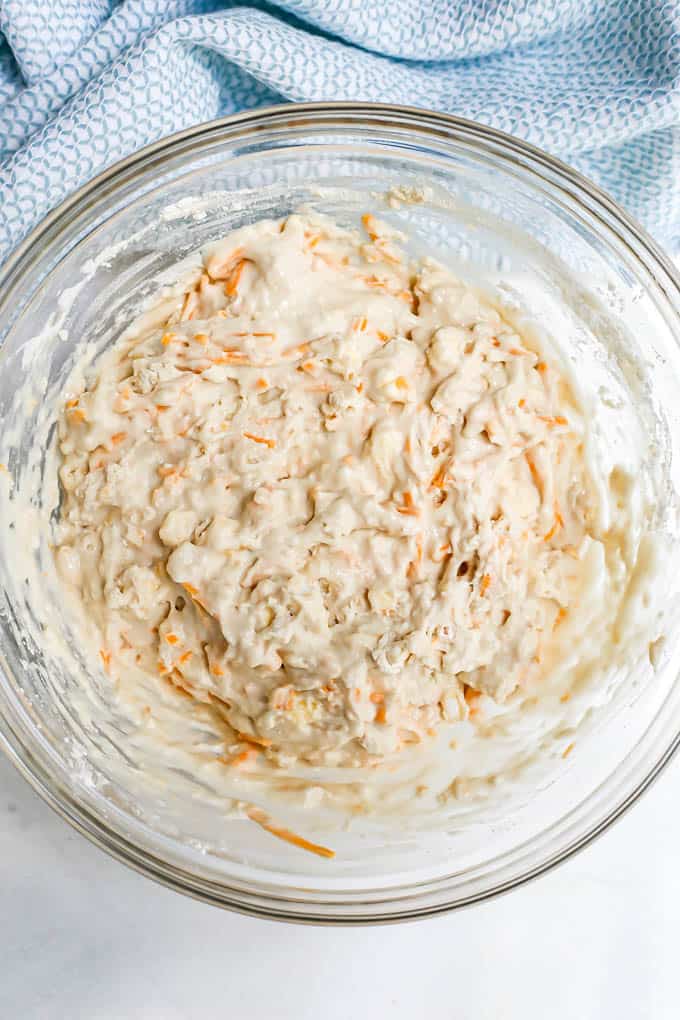 A glass bowl with the batter for some drop biscuits with cheddar cheese