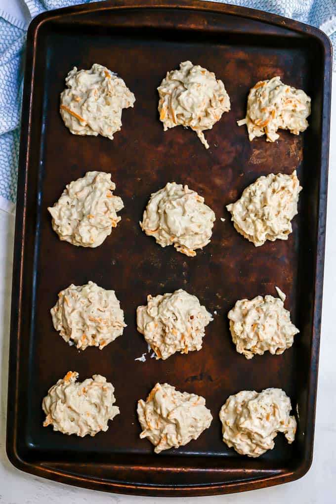 A baking sheet with 12 drop biscuits arranged before they are baked