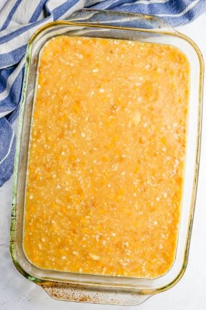 A glass casserole dish with a liquidy corn pudding mixture before being baked