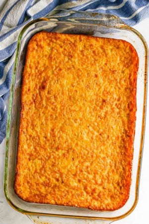 Golden brown corn pudding in a glass casserole dish after being baked in the oven