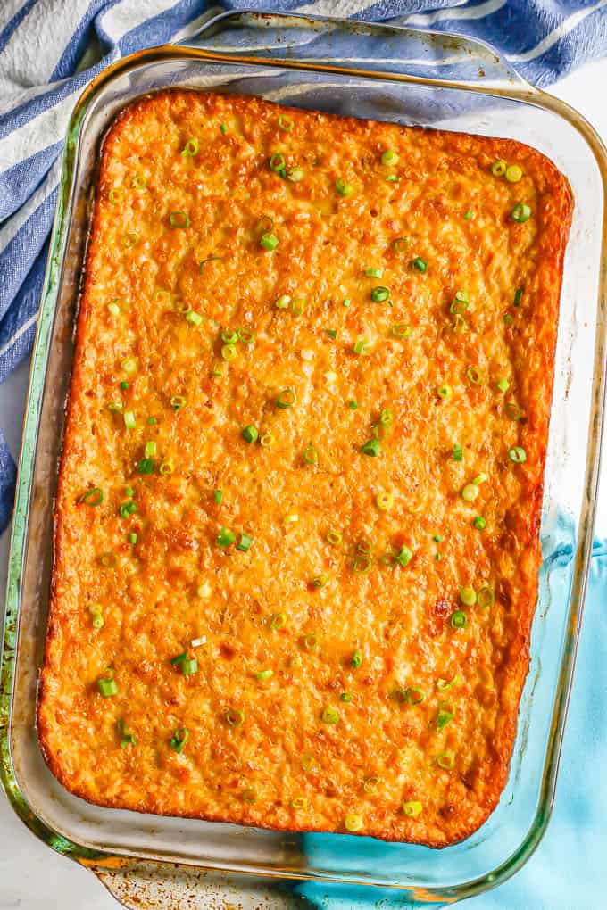 Baked corn pudding casserole in a glass dish with sliced green onions sprinkled on top