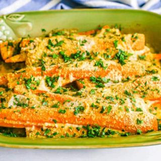 Roasted long strips of carrots in a creamy sauce with browned breadcrumbs on top and a sprinkling of parsley on the dish