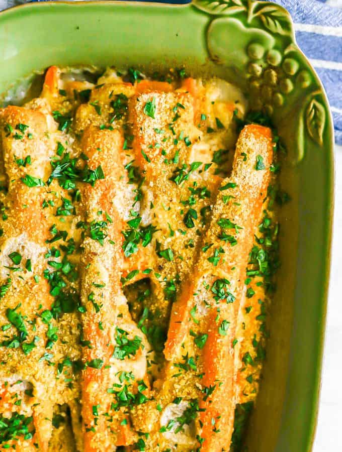 Roasted carrots in a creamy sauce with toasted breadcrumbs on top and chopped parsley sprinkled over the baking dish